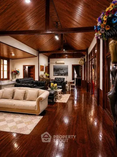 Luxurious living room with high wooden ceilings and elegant furniture, exuding warmth and sophistication.