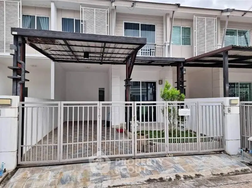Modern townhouse exterior with gated entrance and covered parking area.