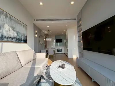 Modern living room with open kitchen, sleek furniture, and large TV