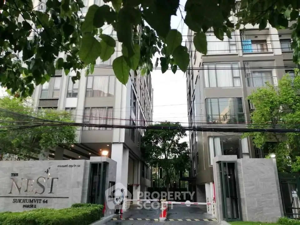 Modern condominium entrance with lush greenery at The Nest Sukhumvit 64, showcasing urban living.