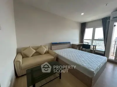 Modern bedroom with city view, featuring a cozy sofa and sleek glass table.
