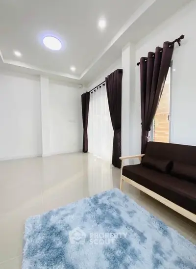 Spacious living room with modern decor, featuring large windows and elegant curtains, perfect for natural light.