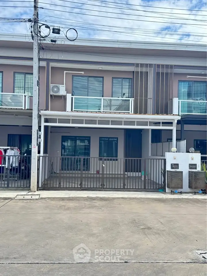 Modern townhouse exterior with balcony and parking space in urban setting.