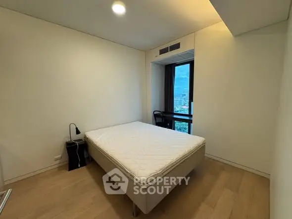 Cozy bedroom with city view, featuring a comfortable bed and modern lighting.