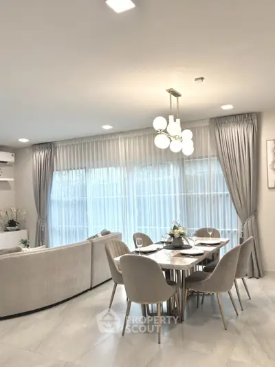 Elegant dining area with modern chandelier and large windows in a spacious living room.