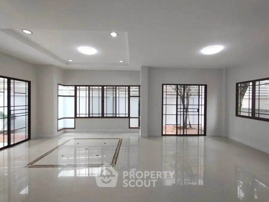 Spacious modern living room with large windows and elegant ceiling lights.