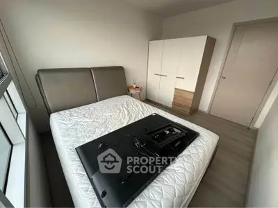 Modern bedroom with sleek wardrobe and large window, showcasing minimalist design and ample natural light.