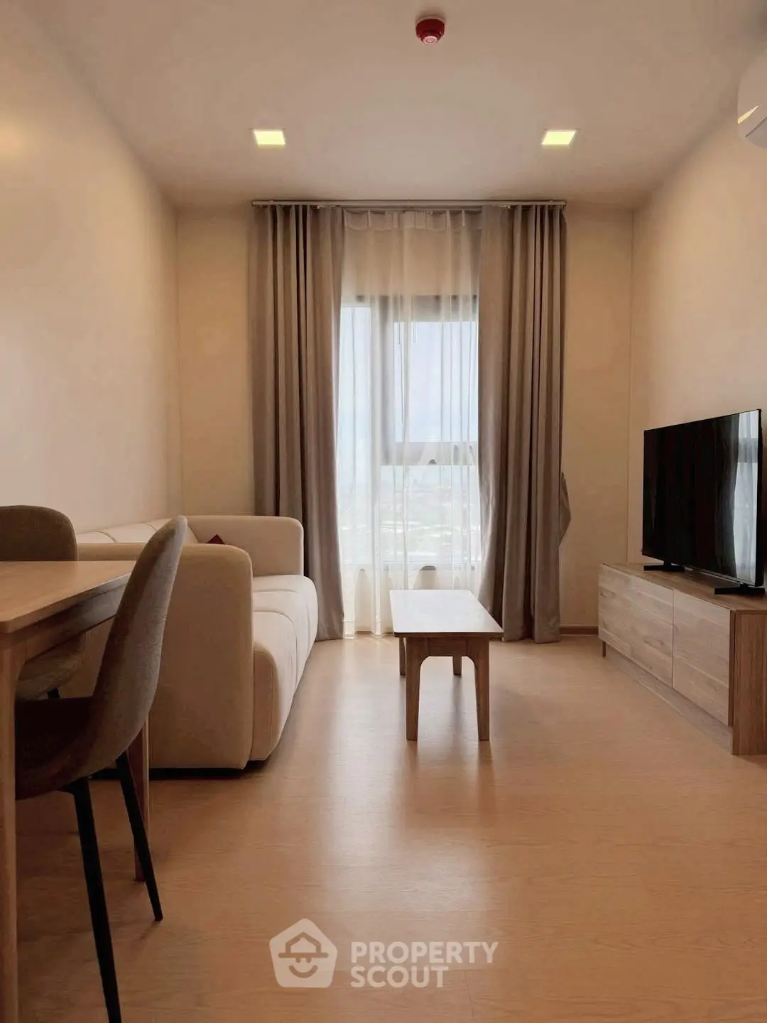 Modern living room with cozy sofa, dining table, and large window for natural light.