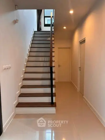 Modern staircase in a sleek hallway with polished floors and ambient lighting.