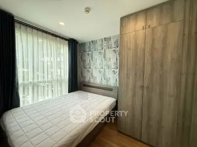 Cozy bedroom with large window and modern wardrobe in stylish apartment.