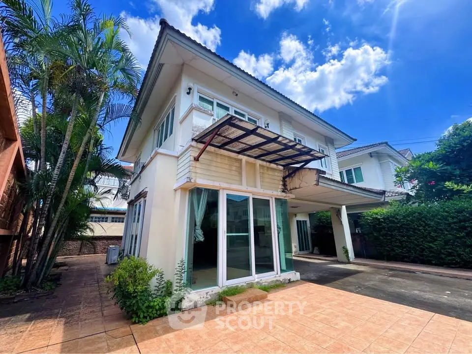 Charming two-story house with spacious driveway and lush greenery under a bright blue sky.