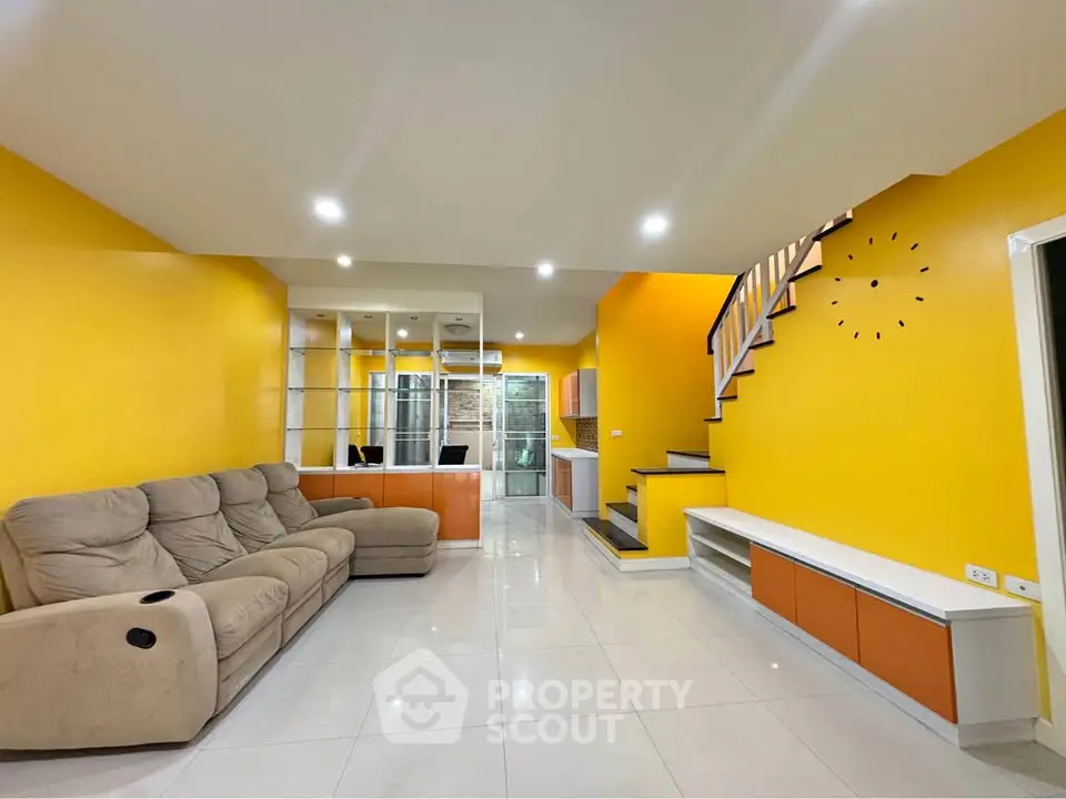 Spacious modern living room with vibrant yellow walls and sleek staircase