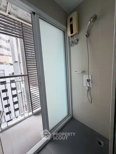 Modern bathroom with shower and sliding glass door leading to balcony view.