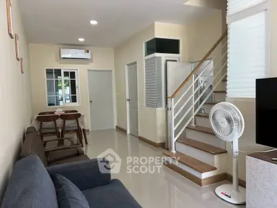 Modern living room with staircase, dining area, and air conditioning in a cozy home.