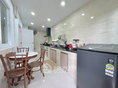 Modern kitchen with sleek cabinets, dining set, and appliances in a bright, well-lit space.