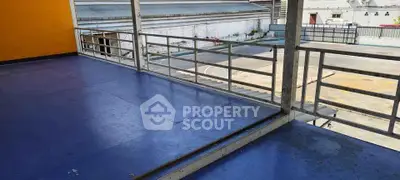 Spacious balcony with vibrant blue flooring and sturdy railing, perfect for outdoor relaxation.