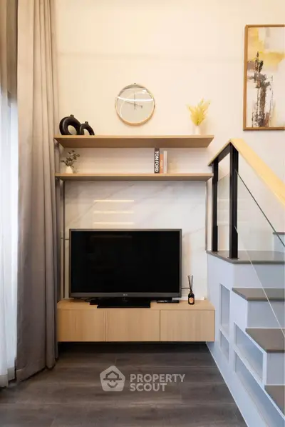 Modern living room with stylish decor and TV unit, featuring elegant shelving and contemporary staircase design.