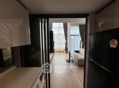 Modern apartment interior with open layout, featuring a cozy living area and sleek kitchen appliances.