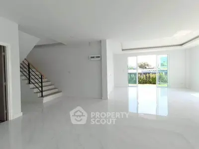 Spacious modern living room with large windows and sleek staircase