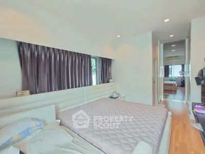 Spacious modern bedroom with elegant decor and large windows for natural light.