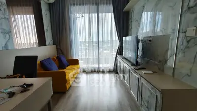 Modern living room with marble walls, large TV, and city view through sheer curtains.