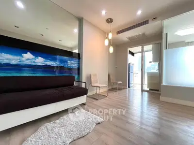 Modern living room with stylish decor and open layout, featuring a scenic wall mural and elegant lighting.
