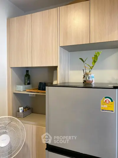Modern kitchen with sleek cabinets and energy-efficient fridge in a stylish apartment.