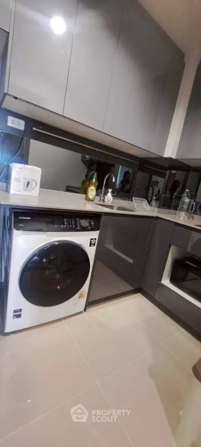 Modern kitchen with sleek cabinetry and built-in appliances, featuring a washing machine and stylish countertops.