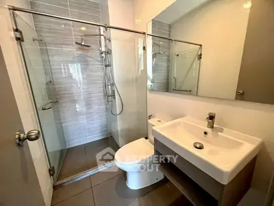Modern bathroom with glass shower and sleek fixtures in contemporary home.