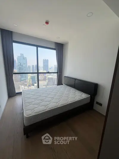 Modern bedroom with stunning city view and large window in high-rise apartment.