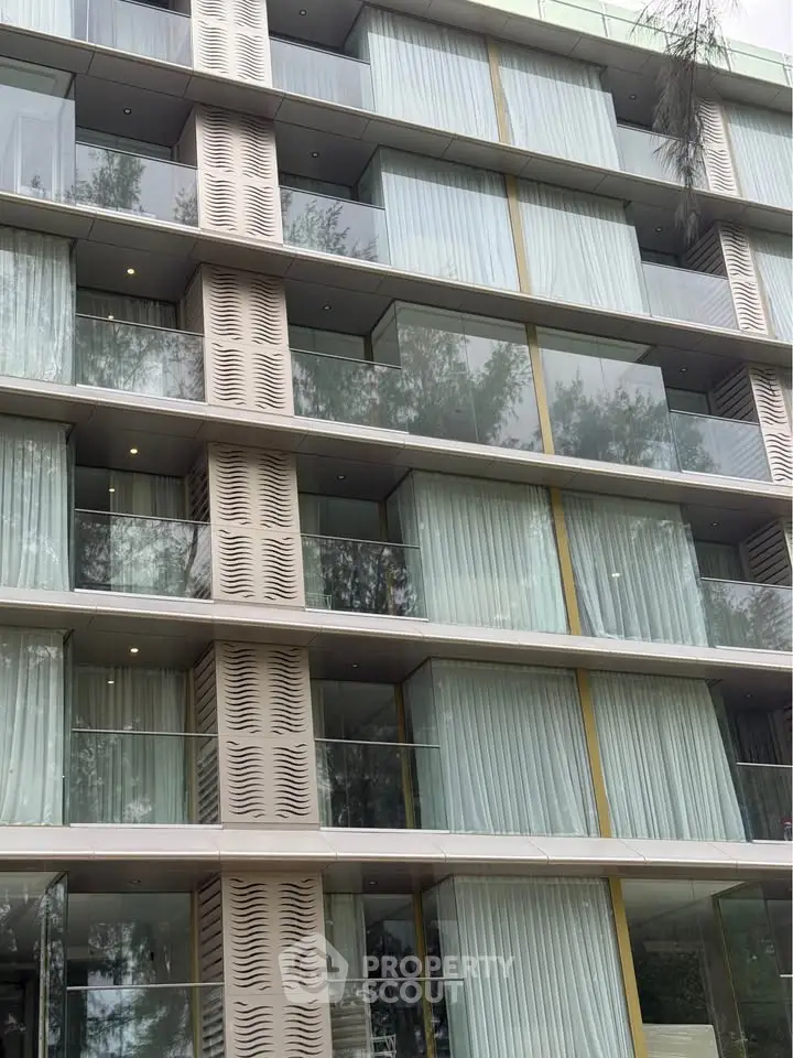 Modern apartment building with glass balconies and sleek architectural design.
