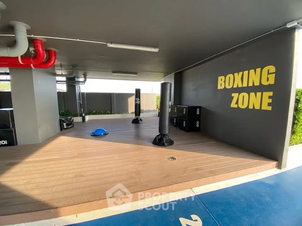 Modern boxing zone in residential building with punching bags and wooden flooring.