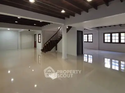 Spacious open-plan living area with polished floors and wooden ceiling beams.