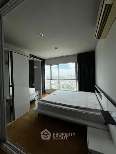 Spacious bedroom with large window offering stunning city views, featuring modern furnishings and ample natural light.