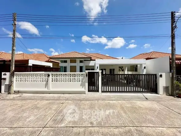 Charming single-story house with modern design and spacious driveway under a clear blue sky.