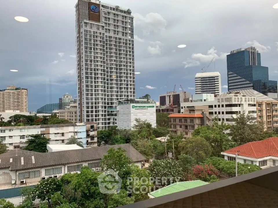 Stunning cityscape view from a high-rise building showcasing lush greenery and modern architecture.