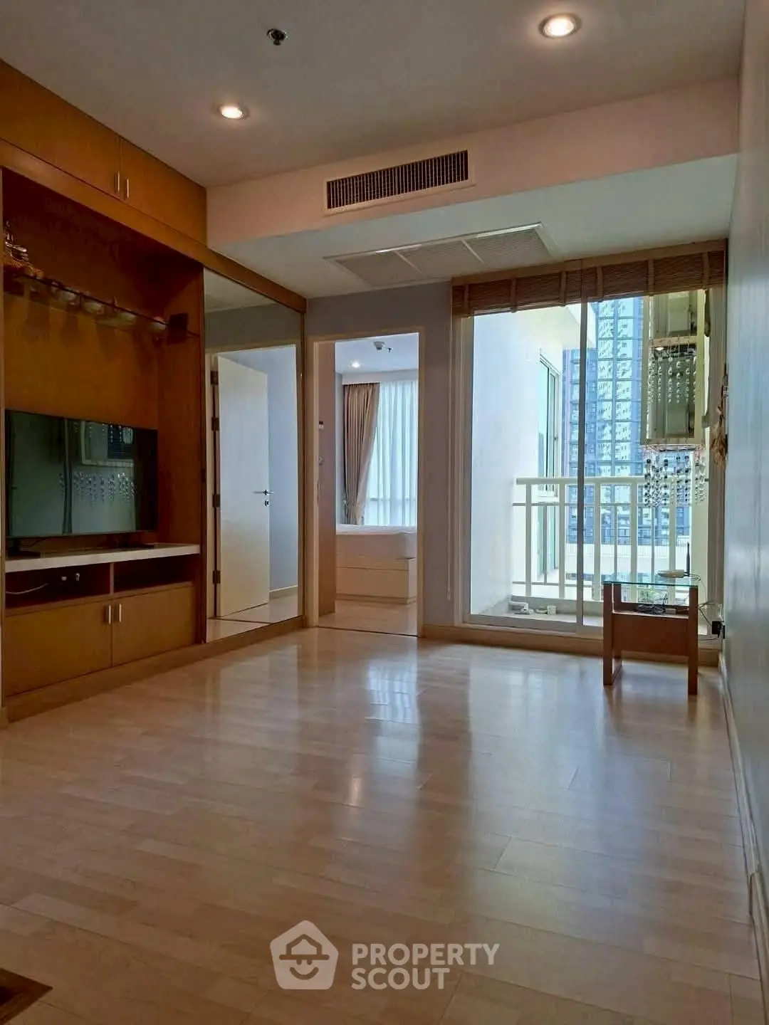 Spacious modern living room with wooden flooring and balcony access in urban apartment.