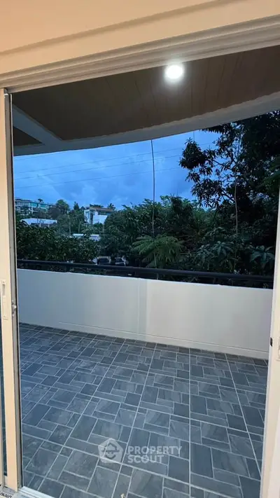Spacious balcony with scenic view of lush greenery and modern tiled flooring.
