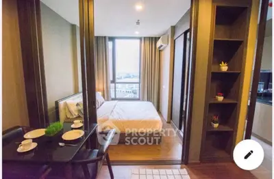 Modern bedroom with wooden flooring, large window, and cozy dining area in a stylish apartment.