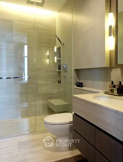 Modern bathroom with glass shower and sleek vanity in luxury apartment.
