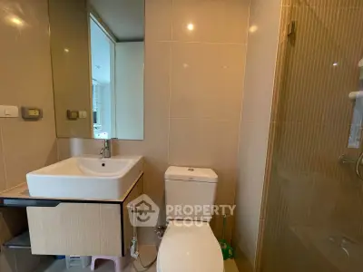 Modern bathroom with sleek fixtures and glass shower enclosure in a contemporary apartment.