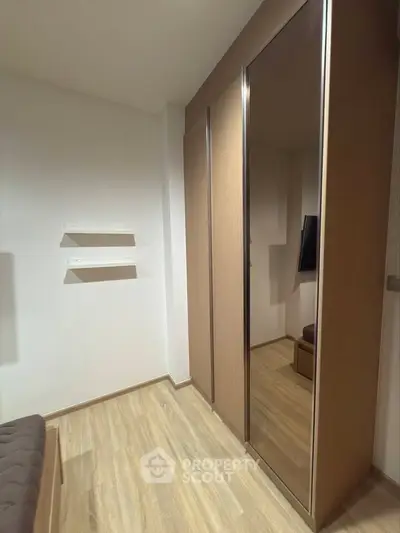 Modern bedroom with sleek mirrored wardrobe and wooden flooring