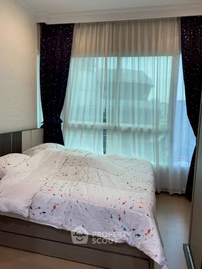 Cozy bedroom with large window and stylish curtains, perfect for relaxation.