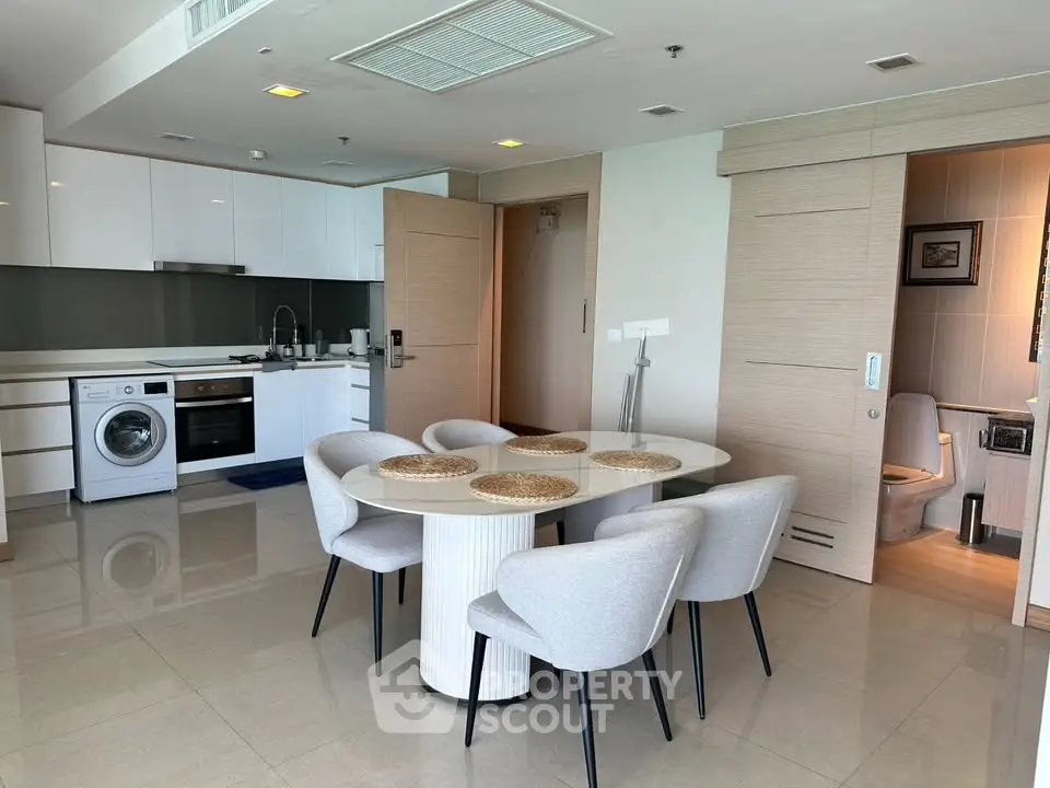 Modern open-plan kitchen and dining area with sleek appliances and elegant furniture.