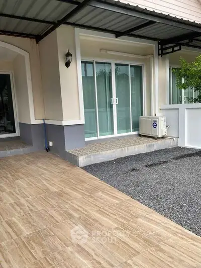Modern home exterior with sliding glass doors and covered patio area.