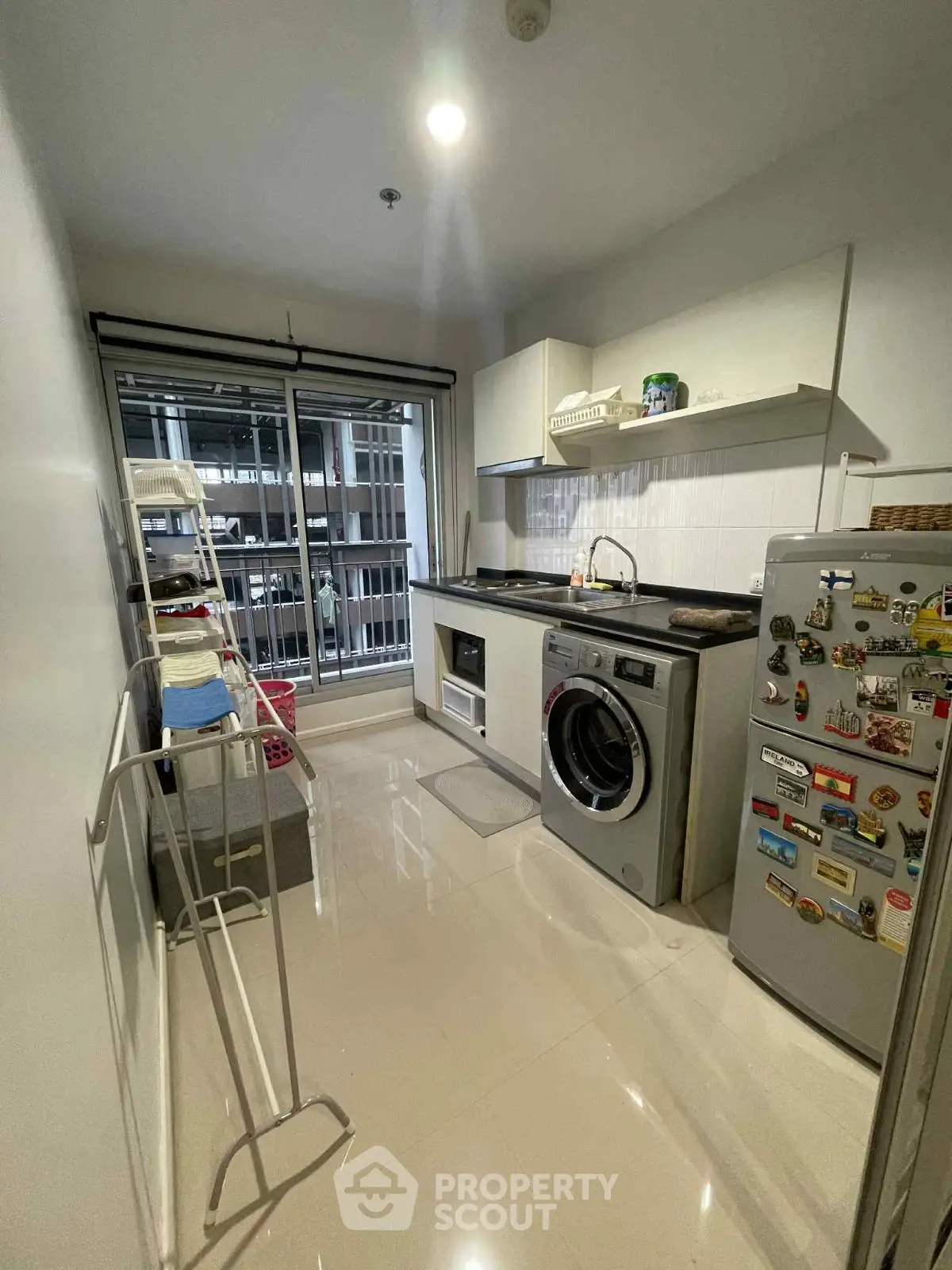 Modern kitchen with washing machine and fridge, sleek design and ample storage space.
