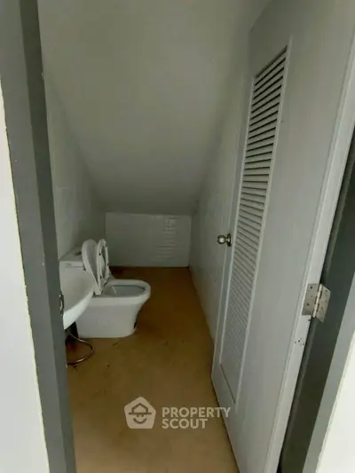 Compact bathroom with sloped ceiling and basic fixtures