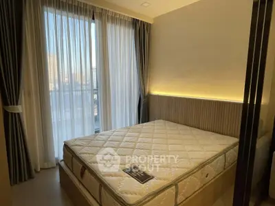 Modern bedroom with large window and elegant curtains, featuring a comfortable mattress and ambient lighting.