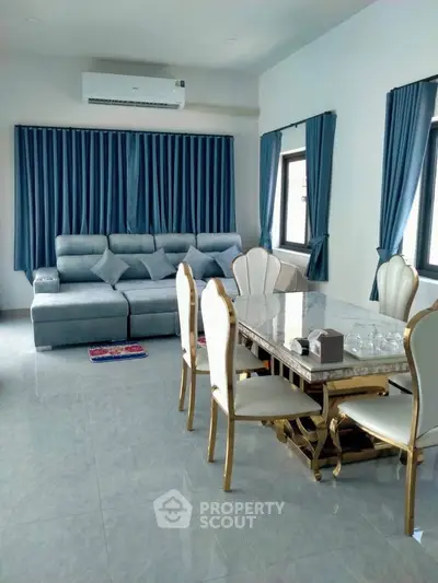 Elegant living room with luxurious dining set and modern sofa, featuring stylish blue curtains and air conditioning.