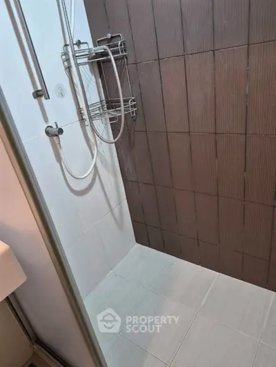Modern bathroom shower area with sleek tiles and chrome fixtures.